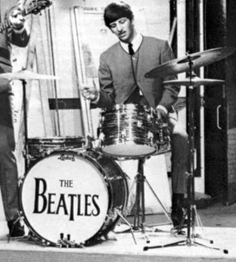 Ringo playing drums, but the focus in this image is on the drop-T design of the Beatles logo on the bass drum. Original source: Beatles Bible, www.beatlesbible.com/gallery/miscellany/drop-t-logo-01/.